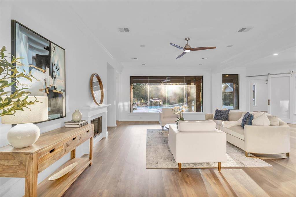 The living room exudes a modern ambiance, featuring a cozy gas fireplace and expansive picture windows that frame stunning views of the pool, complete with serene water fountains and a relaxing spa. It’s the perfect space to unwind and enjoy the beauty of the outdoors from the comfort of indoors.