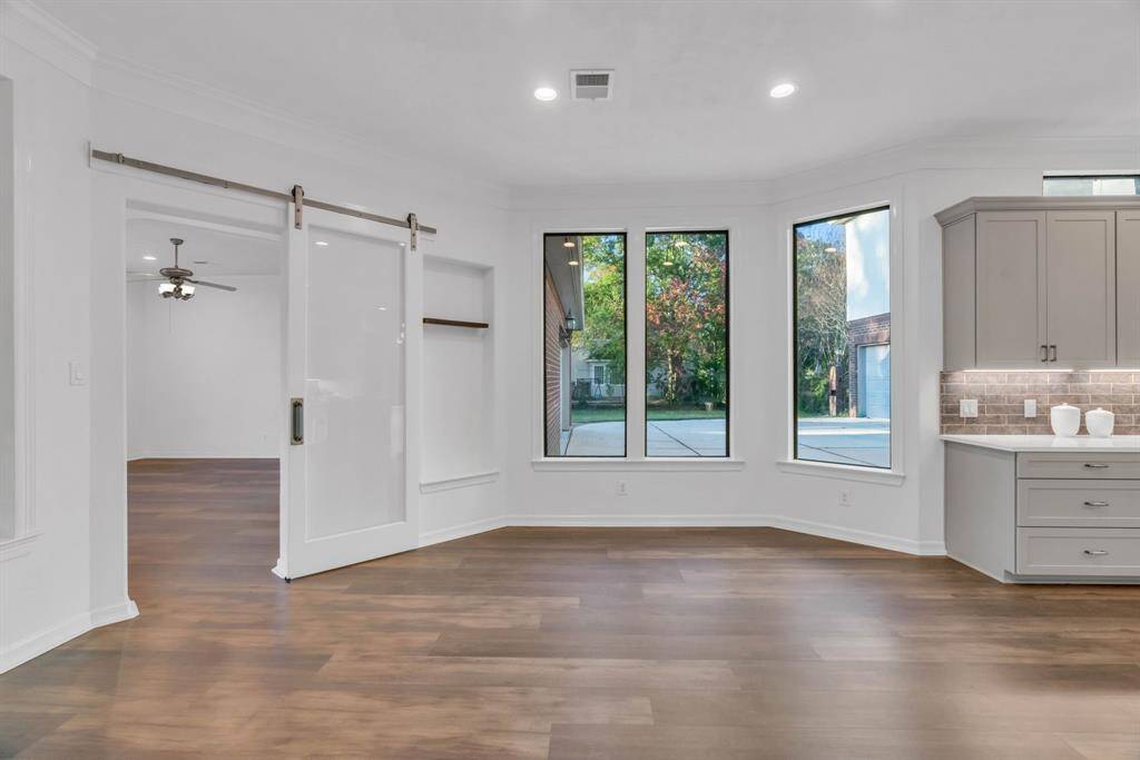 The cozy breakfast nook offers the perfect space for a dining table, creating a charming spot to enjoy meals. Just beyond the sliding doors lies a versatile flex room, providing access to the back garage, a second door to your outdoor paradise, and a convenient full bathroom. This thoughtful layout offers both practicality and seamless connection to the home's beautiful outdoor spaces.
