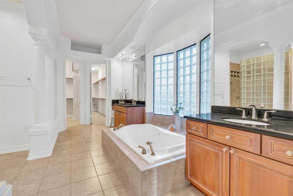 The spacious bathroom features a large Jacuzzi tub and dual sinks, providing ample room for both individuals to enjoy their own space and privacy. It's the perfect retreat for relaxation and comfort.