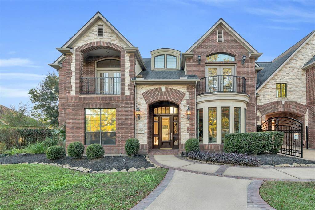The warm, wood front door, adorned with elegant glass panels, welcomes an abundance of natural light into the home, creating an inviting ambiance. Two charming balconies overlook the picturesque front yard, offering serene views and a perfect spot to relax and take in the beauty of your surroundings.