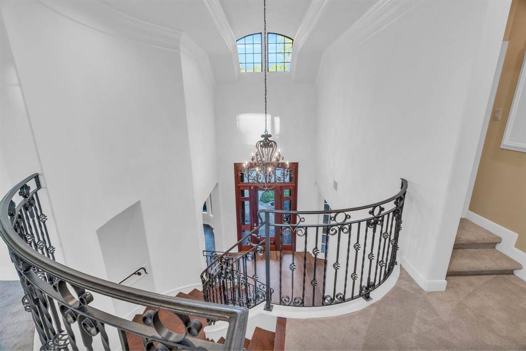 From the game room area, you’ll enjoy a stunning view looking down into the grand foyer, where the spiral staircase and elegant chandelier create a dramatic focal point, enhancing the open and airy atmosphere of the home.