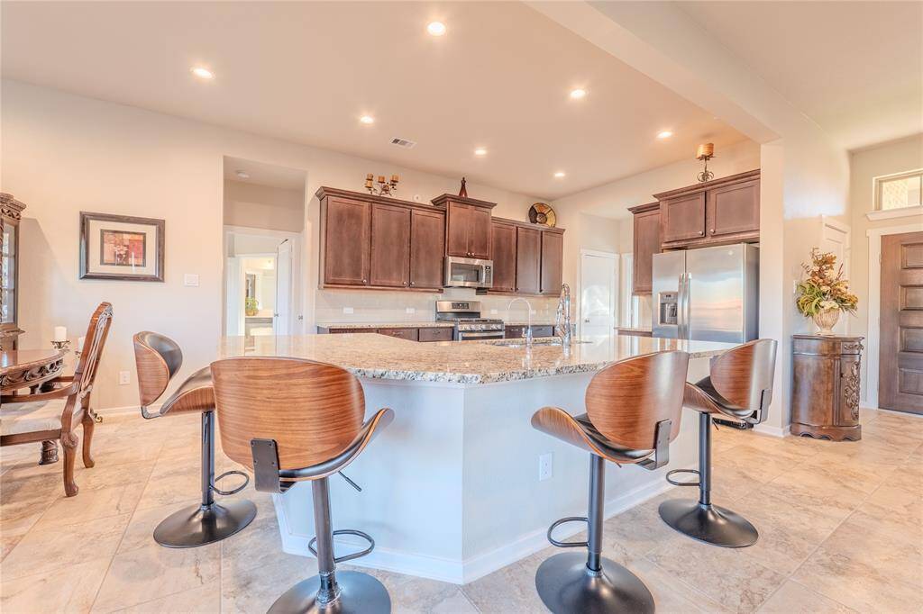 The kitchen boasts a spacious granite breakfast bar, offering ample seating and a perfect spot for casual meals or entertaining guests.