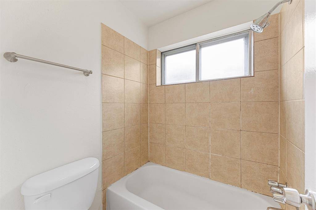 This bathroom features a clean, neutral design with beige tile walls surrounding a white bathtub.