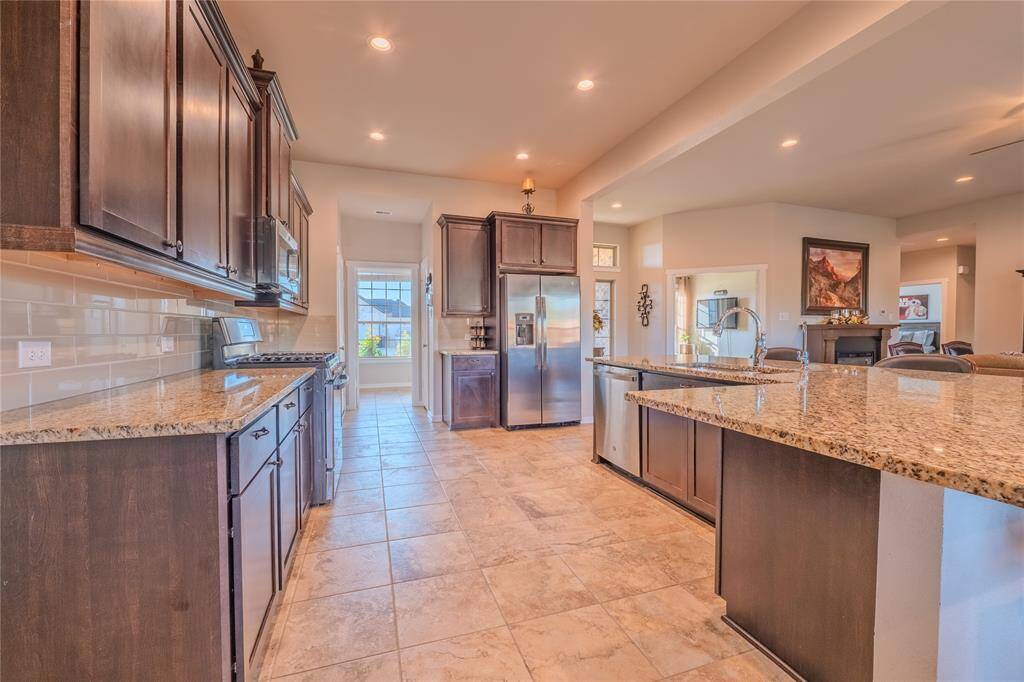 Stainless steel appliances, dark wood cabinetry, and granite countertops define this stylish and functional kitchen