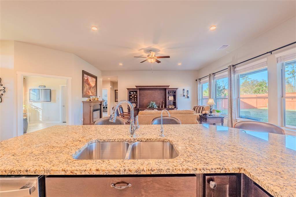 The kitchen island with a dual-basin sink and granite countertops provides a central gathering point with a view of the family room and backyard, creating a seamless flow for entertaining.