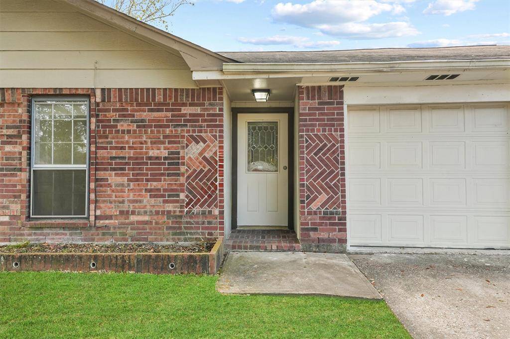 This photo showcases the front entrance of a home with a brick exterior, featuring a welcoming door with decorative glass and an attached garage. The well-maintained lawn adds curb appeal.