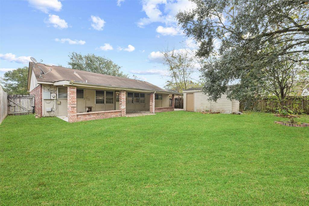 Spacious backyard featuring a covered patio area, a detached shed, and lush green lawn, ideal for outdoor activities and relaxation.