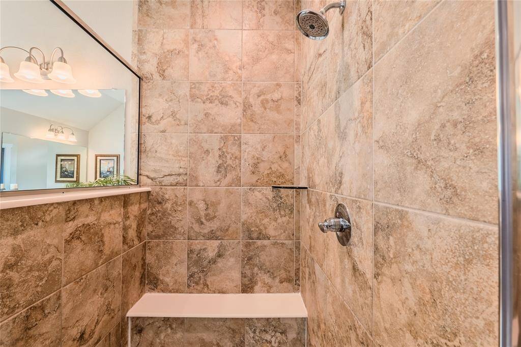 The primary bath includes a beautifully tiled walk-in shower with a glass enclosure, offering a perfect blend of style and functionality.