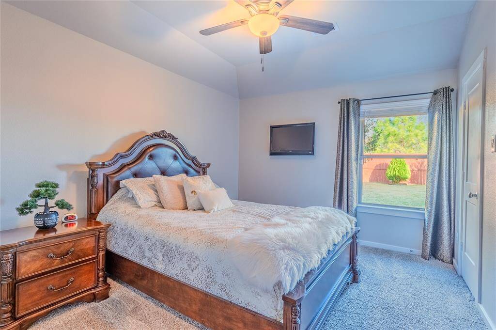A cozy third bedroom boasts soft carpet flooring and a ceiling fan, providing comfort and functionality for guests or family members