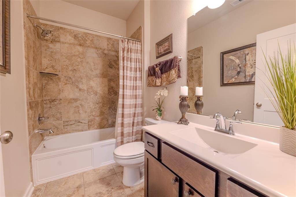 The secondary bathroom features a fully tiled shower and bathtub combo with modern fixtures