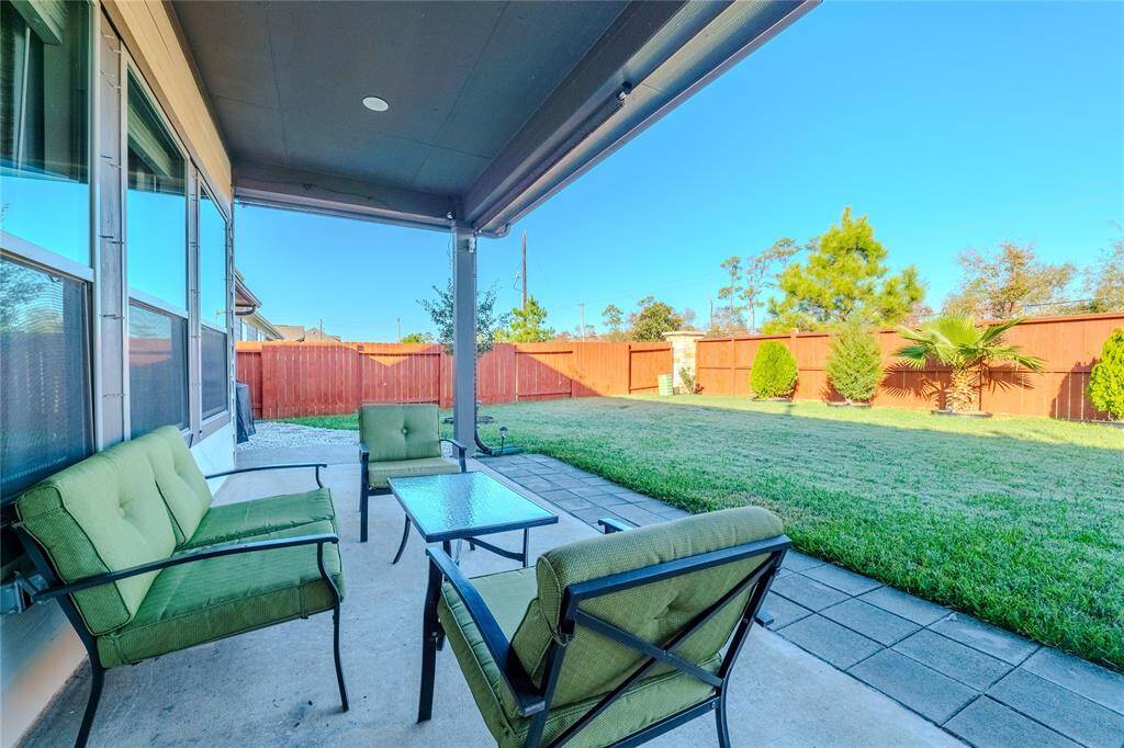 The covered patio creates an inviting outdoor retreat, ideal for relaxing or entertaining guests while enjoying the serene backyard setting.