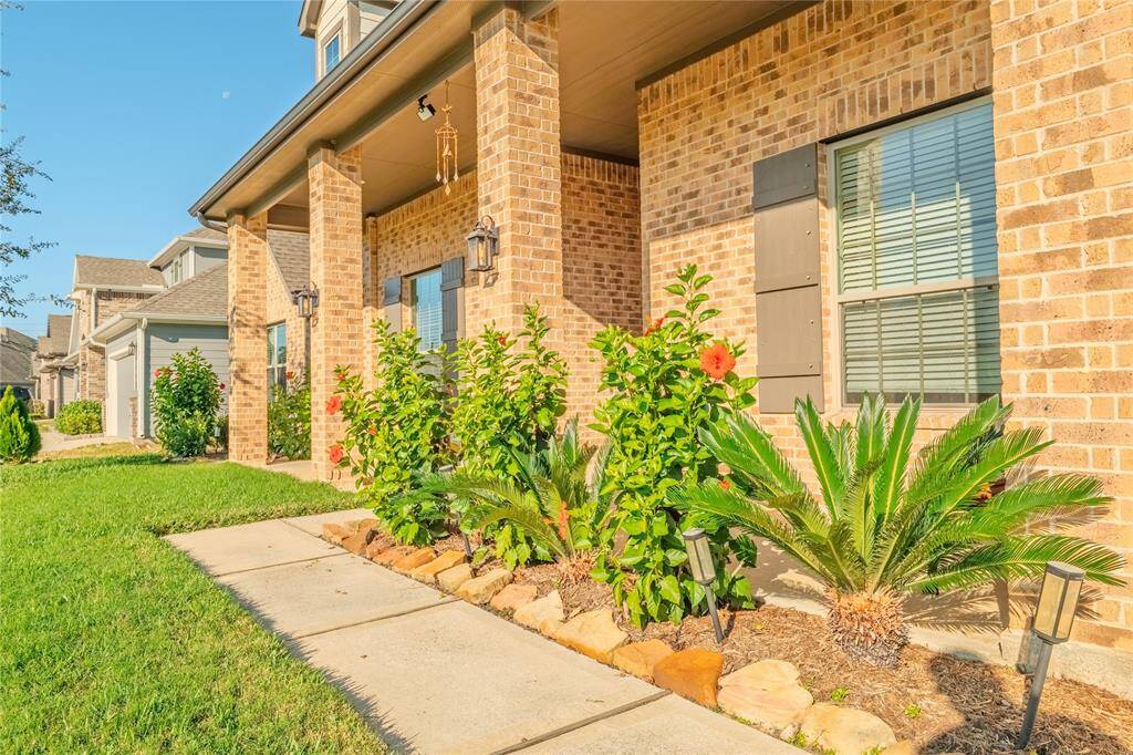 The wide walkway leads to a grand covered porch, offering a warm and welcoming entryway that invites you to step inside.