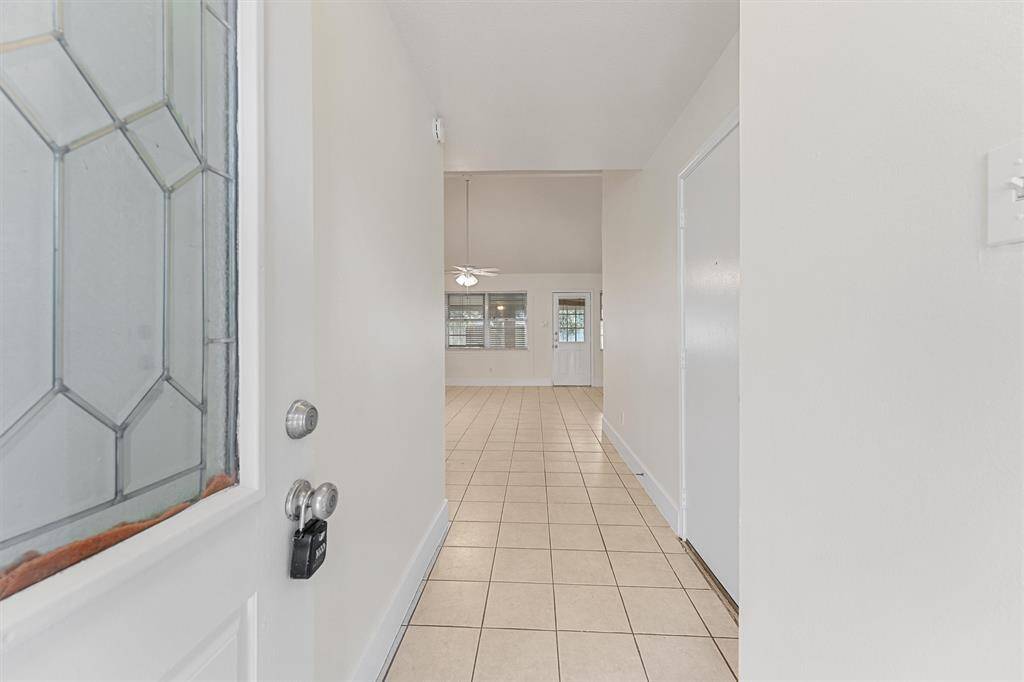 Bright entryway with tiled floors leads to an open living area featuring a vaulted ceiling and large windows for lots of natural light.