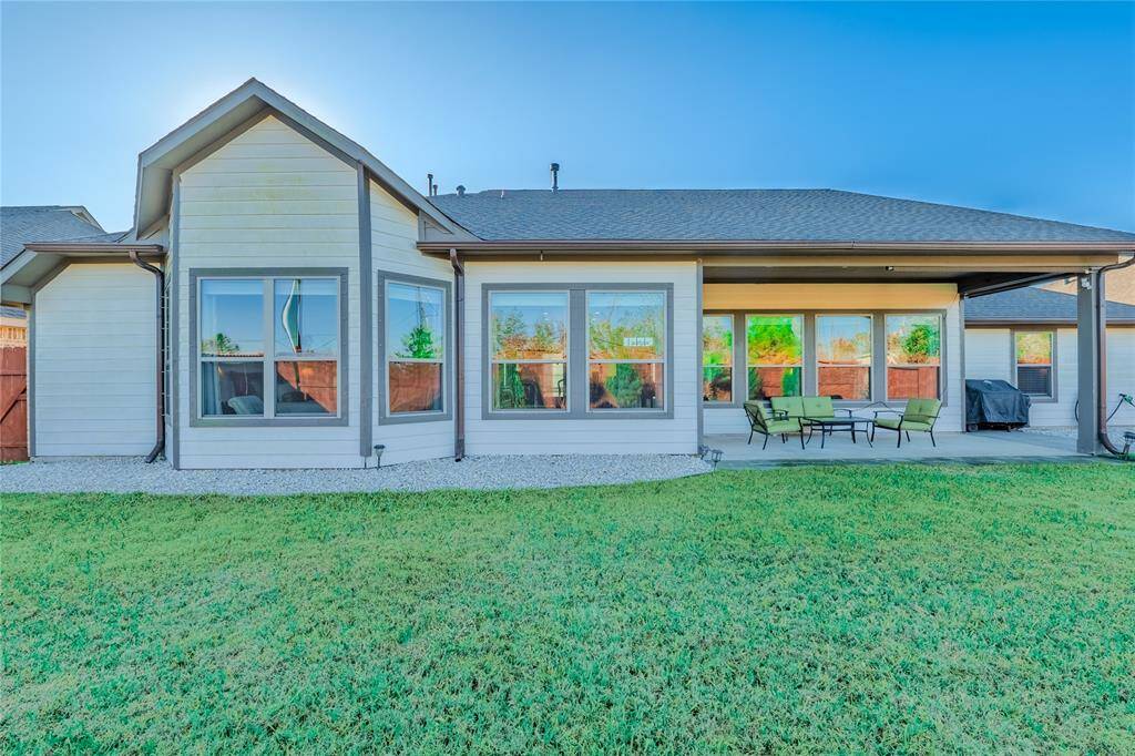 Close up view of the back of the house with covered patio and large windows.