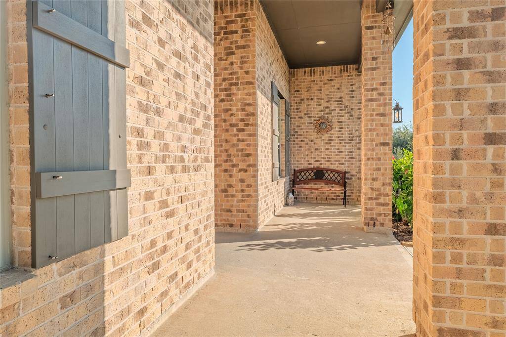 The charming covered front porch, framed by a brick exterior, offers a cozy spot to sit and enjoy the neighborhood atmosphere.