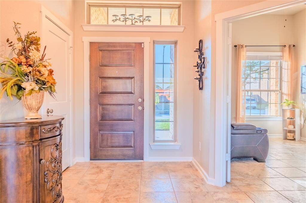The welcoming front entry features a rich wooden door with windows above and to the side, allowing natural light to brighten the space while adding a touch of elegance.