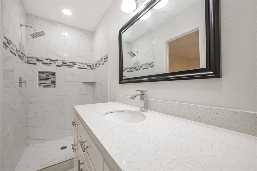 Indulge in this luxurious bathroom complete with modern tilework, a chic vanity, and updated fixtures for a spa-like experience.