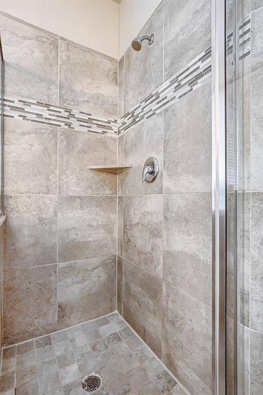 The shower features beautiful tile work with a modern design and a sleek glass door