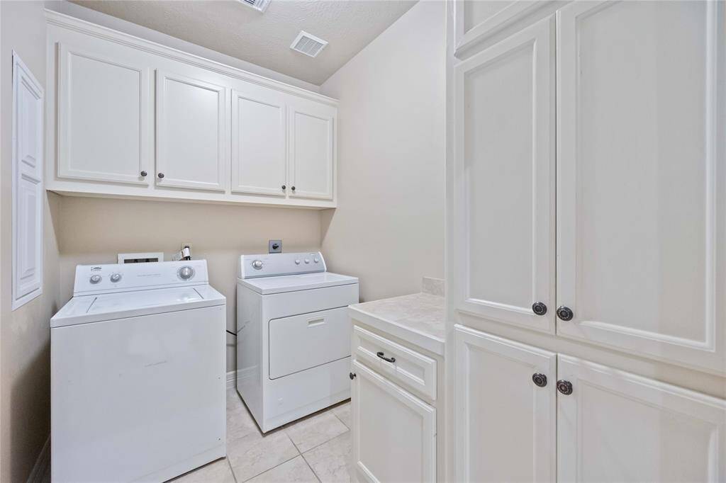 This spacious walk-in closet features ample shelving, hanging rods, and built-in drawers, all with a sleek white finish. Perfect for organized storage and easy access to clothing and accessories.