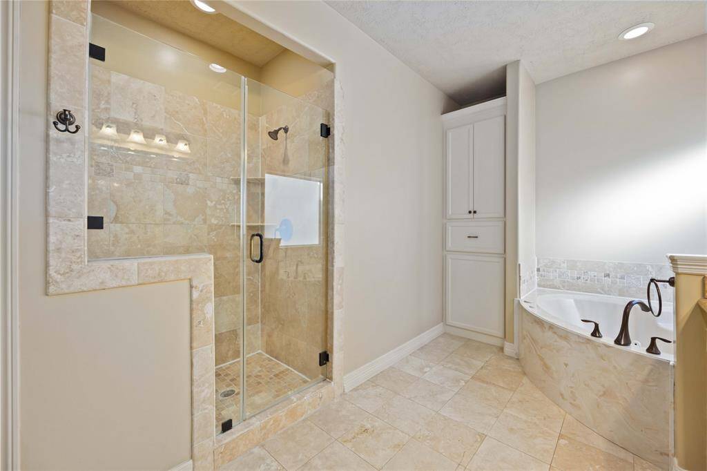 Luxurious corner bathtub with elegant fixtures and ample natural light from a frosted window.