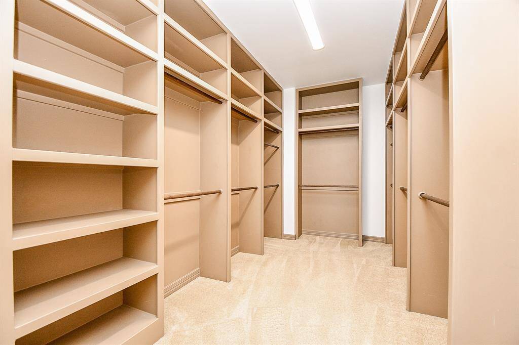 The photo shows a spacious primary bedroom walk-in closet with ample shelving, hanging rods, and integrated lighting, ideal for organized storage and wardrobe management.
