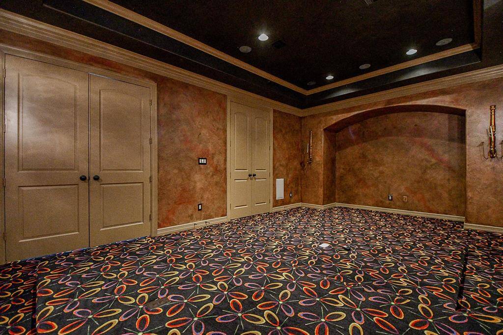 The Media room features a bold, patterned carpet, two sets of double doors, and a recessed ceiling with lighting. The walls have a textured finish, and there's an alcove that could serve as a display or entertainment area.