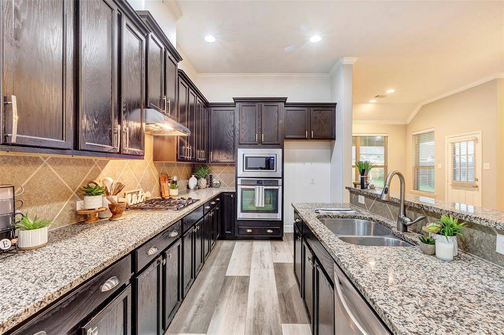 Granite countertops, a spacious island with a sink, and a breakfast bar make this kitchen as functional as it is stylish.