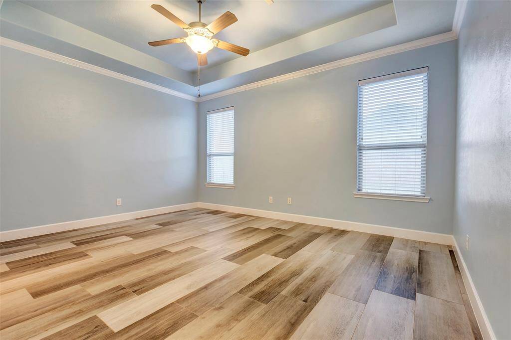 Spacious and versatile, the primary bedroom offers room for a king-sized bed and seating area, featuring fresh paint, a tray ceiling, stunning floors, and upgraded extra-wide baseboards for a polished look. The windows overlook the large backyard.