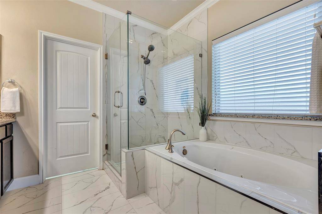 The recently updated primary bathroom features an enlarged shower with seamless glass doors, a jetted tub and gorgeous marble looking floors. It is such a refined, relaxing and elegant space!