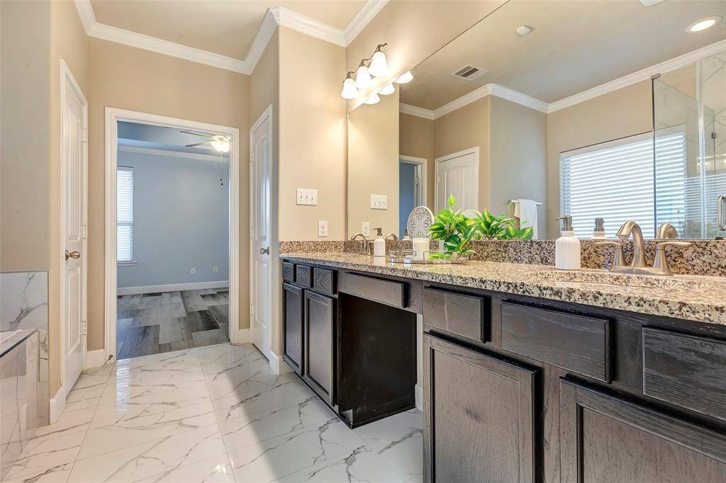 The primary bathroom features a double door entry, tall ceilings, a large vanity with granite countertops, two sinks, a private water closet and large linen closet.