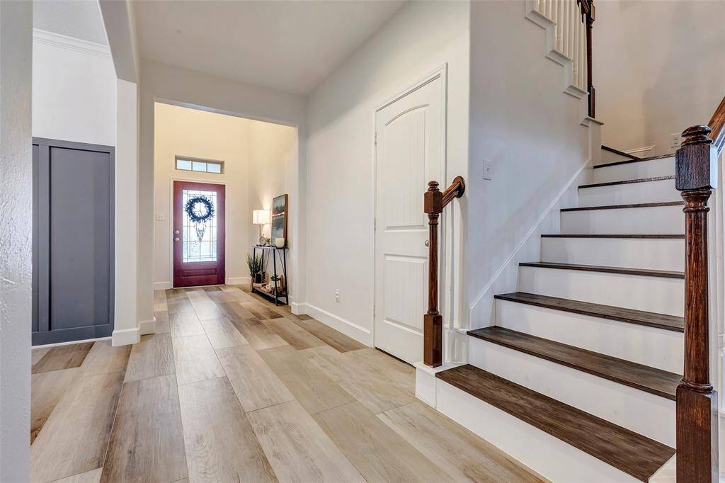 The elegant staircase features newly added wood treads and leads to 3 bedrooms, 2 bathrooms, the game room, and the media room. The door beside the stairs opens to a spacious under-the-stairs closet for added storage.