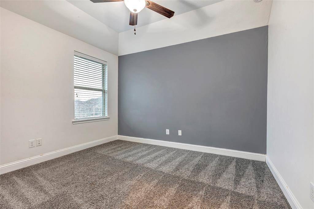 Bedroom #4 offers a large closet, ceiling fan, and views of the backyard and adjacent greenspace. The accent wall makes the space feel inviting and cozy.