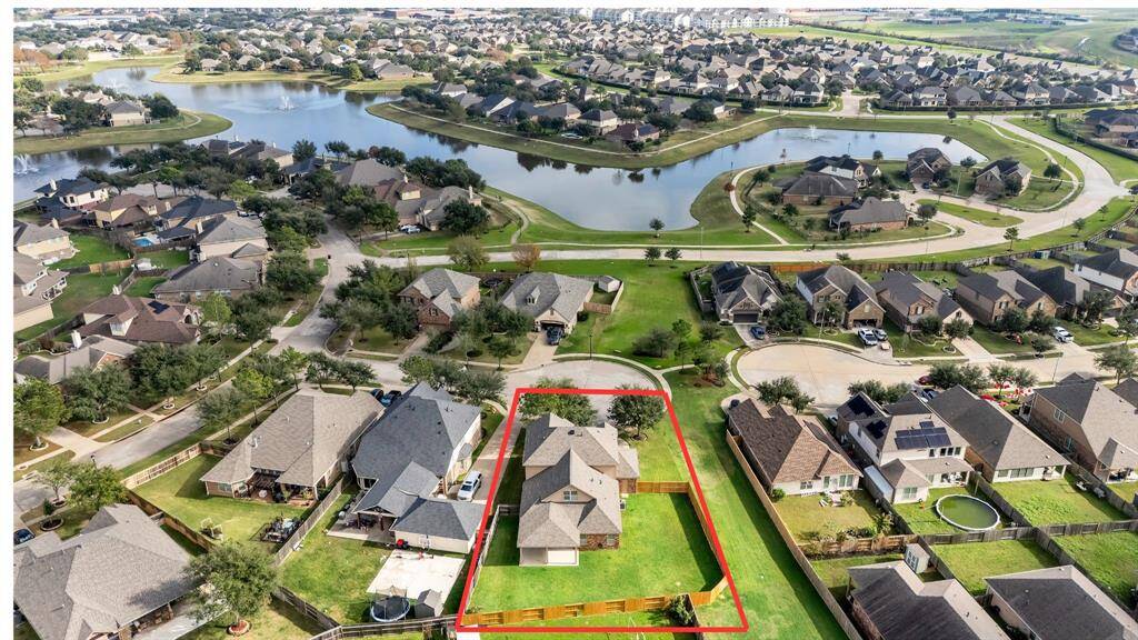 This aerial view of 8303 Dakota Hill Ct highlights the serene neighborhood pond with its scenic walking trail and the added bonus of a greenspaces in front and next door.