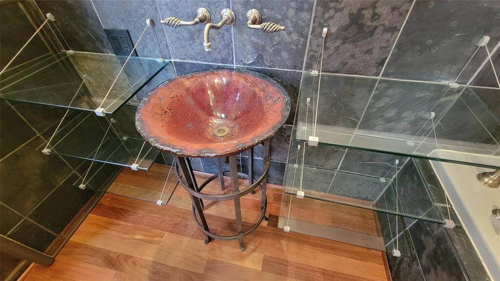 Primary bath art glass sink with designer custom metal pedestal. Unique glass shelves.