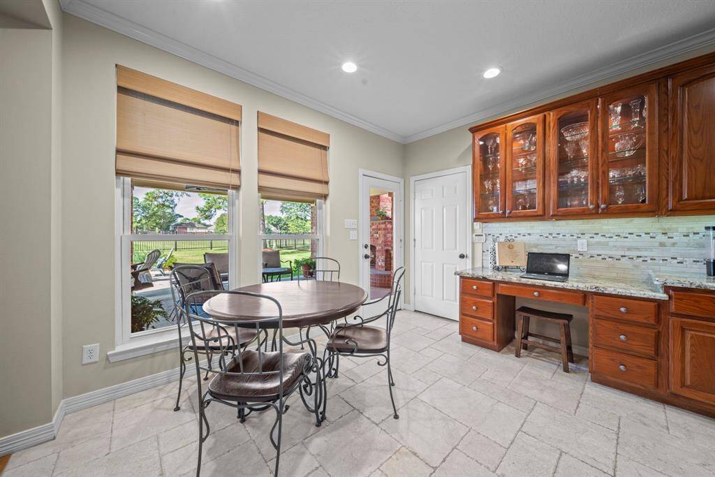 Overlooking the backyard and golf course - the morning area features pull down window coverings, tile flooring, crown molding & recessed lighting. Including a chefs desk and custom glass featured cabinetry, perfect to store cookbooks or your finest dining ware!