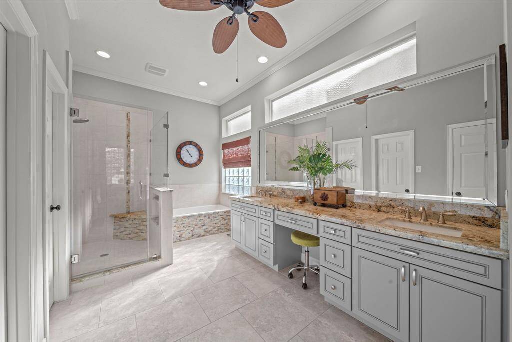 The primary en-suite features tile flooring, crown molding, recessed lighting, a ceiling fan, an updated vanity with Quartz countertops, double sinks and updated cabinetry!