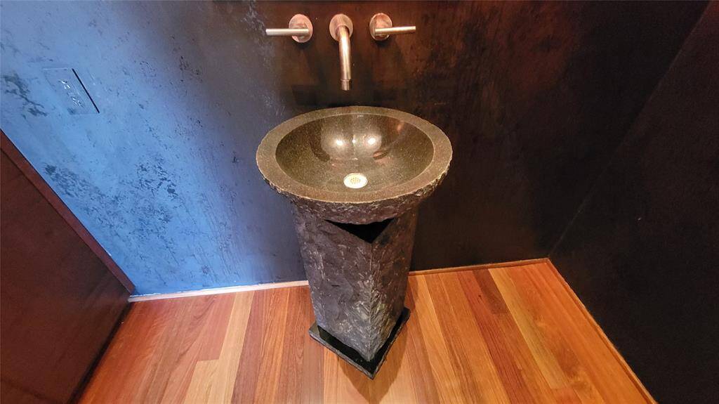 Very Modern stone pedestal sink in powder bath with Venetian plaster walls.