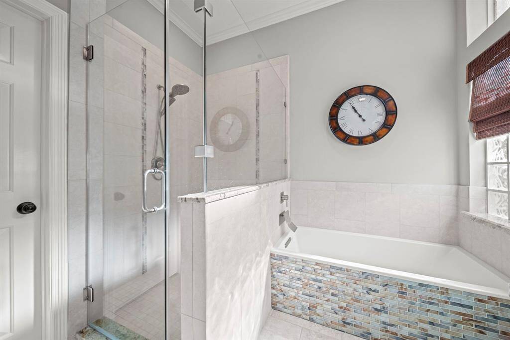 A custom seamless shower with bench seating complements the luxurious standalone bathtub, beautifully accented with tile detailing.