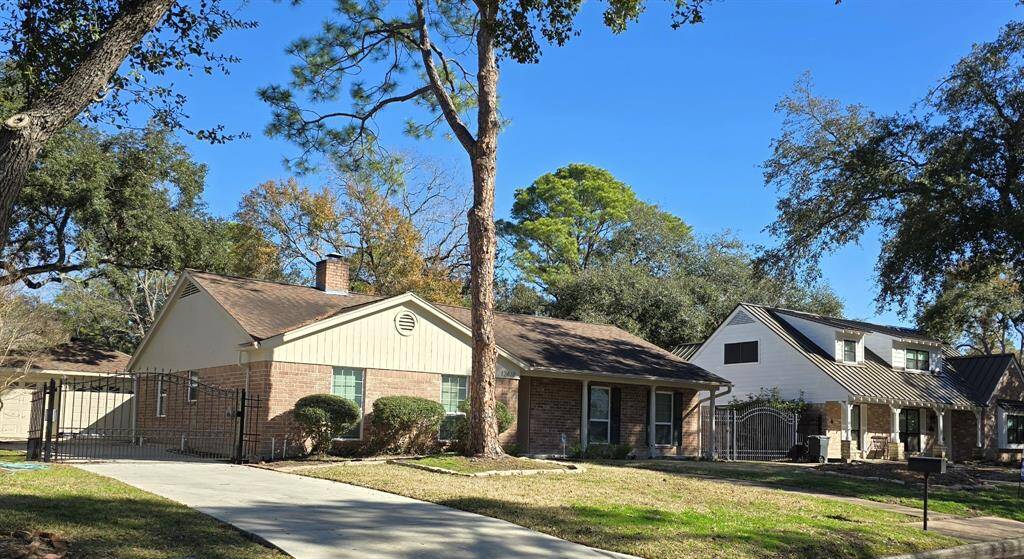 Charming single-story brick home with automatic gate, and long driveway. Spacious lot with mature trees and a walkway leading to the front door into a cozy porch.