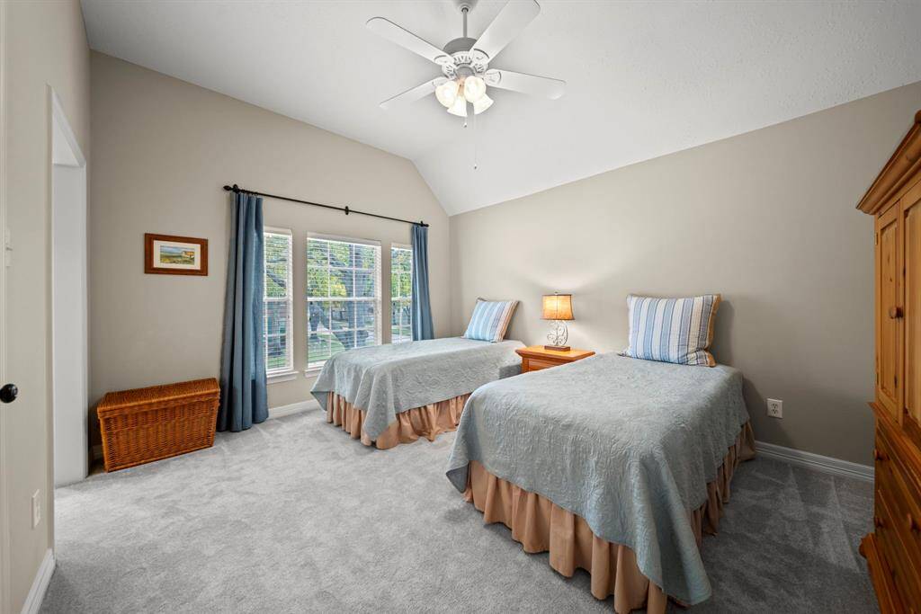 Secondary bedroom overlooks the serene front yard, featuring a walk in closet, carpet, soaring ceilings, a ceiling fan, 2" blinds and an attached Jack & Jill bathroom!