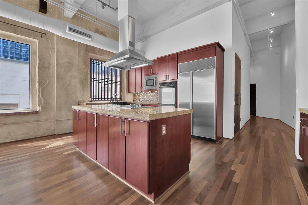 Cherry cabinets, cook top in island, built in sub zero refrigerator, double oven and chiseled edge granite countertops highlight kitchen.