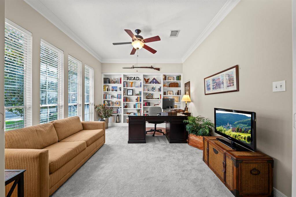 Open French doors to a study with high ceilings, built-in bookshelves, 2" blinds, a ceiling fan and double crown molding!