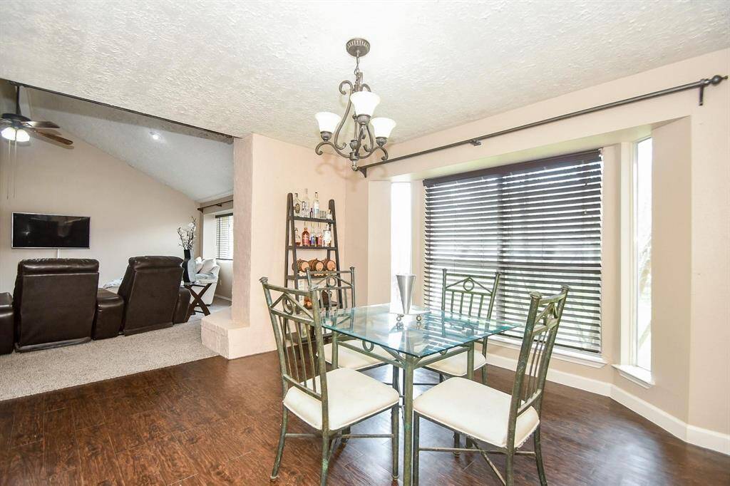 Dining area with large bay windows, rich wood flooring, and an open layout perfect for gatherings.