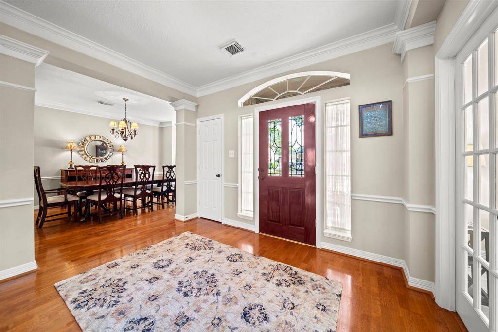 The entryway opens to a stunning dining room, seamlessly extending the elegant wood flooring.