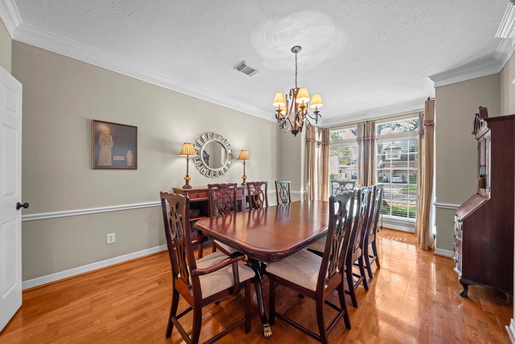 Spacious dining room with an elegant chandelier, wood flooring, double crown molding, chair molding, 2" blinds and easy access to the kitchen!