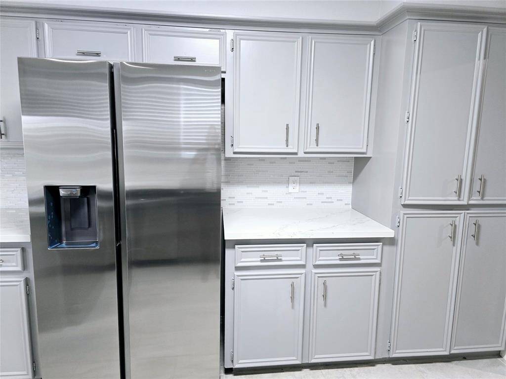 New double-door stainless still refrigerator included.  The subtle tile backsplash adds elegance to the space that has cabinetry with new hardware.