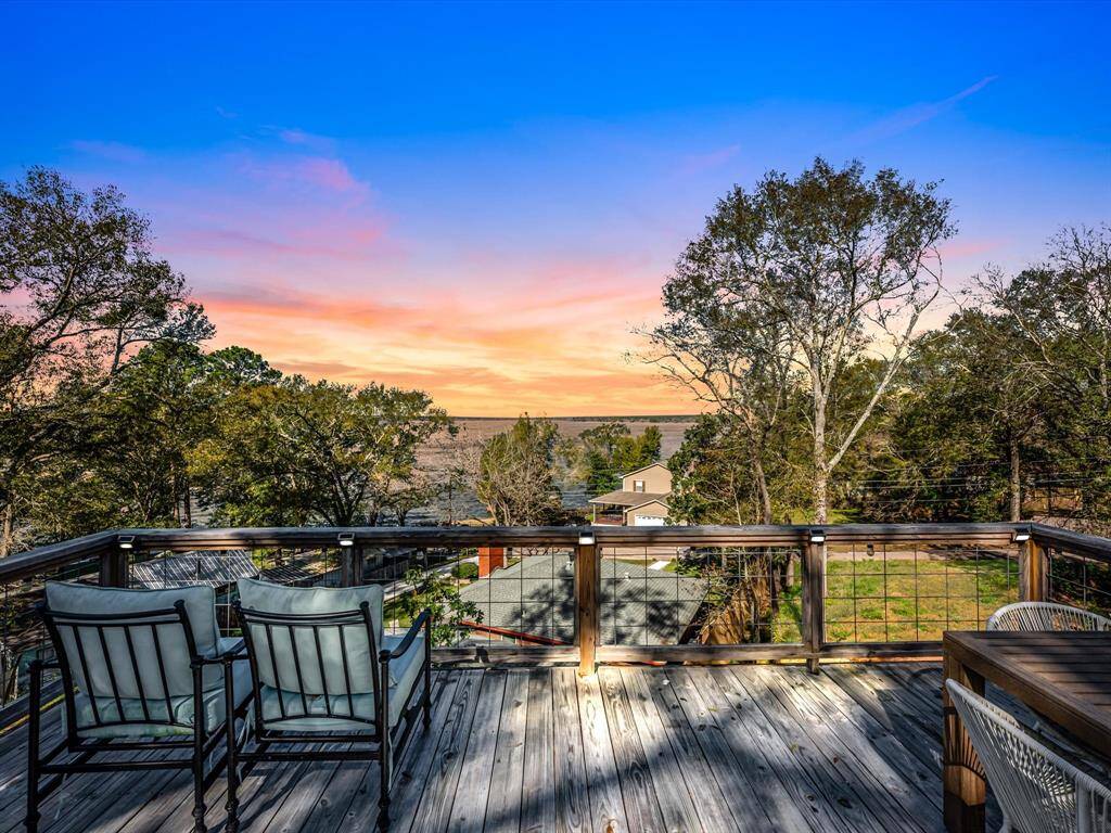 Spacious deck with comfortable seating, offering stunning views of a lush landscape and a serene body of water. Perfect for enjoying sunsets and outdoor relaxation.