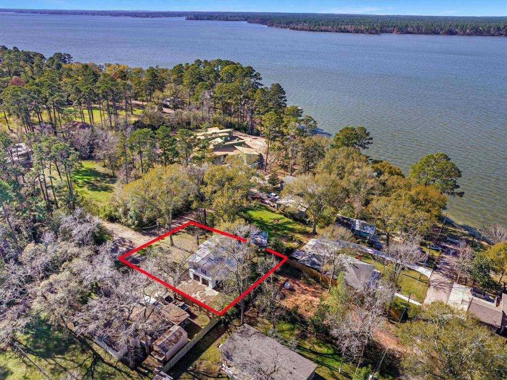 This aerial photo showcases a charming lakeside property, highlighted in red, surrounded by lush trees and offering picturesque views of the water. Perfect for nature lovers seeking tranquility.