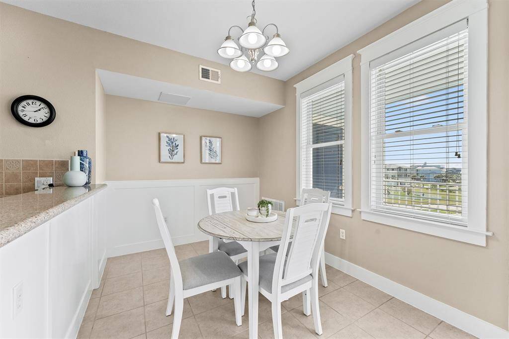 This bright and inviting dining area features large windows that offer scenic views and plenty of natural light. The ample wall space provides an ideal canvas for art or family photos, adding a personal touch to the space.