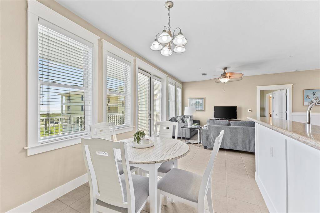 Expansive windows line the dining area, creating a cheerful and welcoming environment. The open layout enhances the sense of space and connection to the adjoining living area.